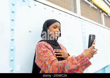 Lächelnde junge Frau im Hijab, die Selfie macht Stockfoto