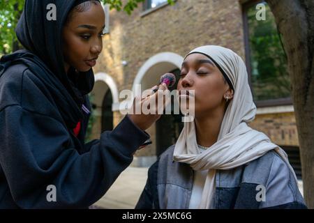 Junge Frau, die Hijab trägt und sich in der Stadt schminkt Stockfoto