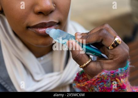 Nahaufnahme einer Frau, die Lippengloss auf die Lippen von Freunden aufträgt Stockfoto