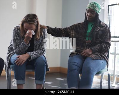 Frau tröstet weinende Frau in der Gruppentherapie Stockfoto