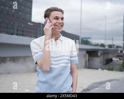 Lächelnder Mann, der in der Stadt telefoniert Stockfoto