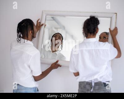 Teenager (16-17) Mädchen und Junge hängen Spiegel an der Wand Stockfoto