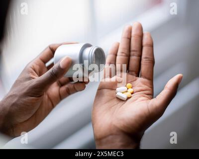 Nahaufnahme einer Person, die Pillen in die Hand gießt Stockfoto