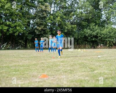 Kinder (8–9) in Uniformen, die auf dem Fußballfeld trainieren Stockfoto