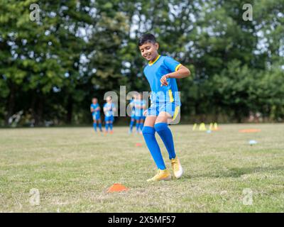 Kinder (8–9) in Uniformen, die auf dem Fußballfeld trainieren Stockfoto