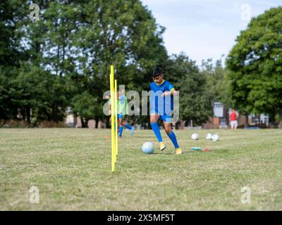 Kinder (8–9) in Uniformen, die auf dem Fußballfeld trainieren Stockfoto