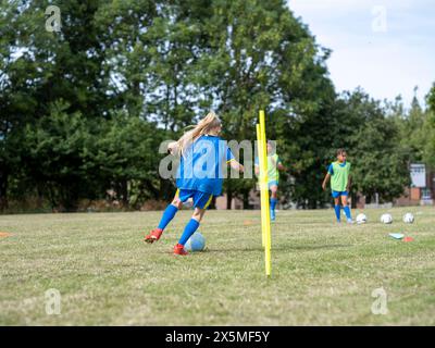 Kinder (8–9) in Uniformen, die auf dem Fußballfeld trainieren Stockfoto