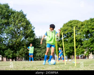 Kinder (8–9) in Uniformen, die auf dem Fußballfeld trainieren Stockfoto