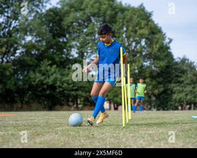 Kinder (8–9) in Uniformen, die auf dem Fußballfeld trainieren Stockfoto