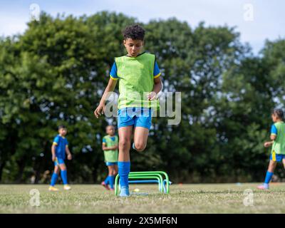 Kinder (8–9) in Uniformen, die auf dem Fußballfeld trainieren Stockfoto