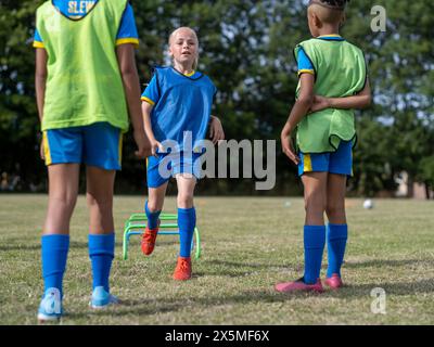 Kinder (8–9) in Uniformen, die auf dem Fußballfeld trainieren Stockfoto