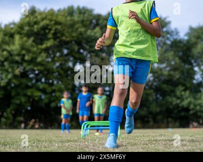 Kinder (8–9) in Uniformen, die auf dem Fußballfeld trainieren Stockfoto