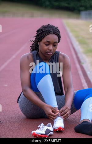 Sportliche Frau bindet Schuhe auf der Laufbahn Stockfoto