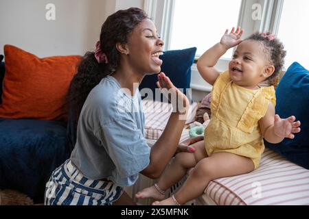 Mutter, die zu Hause ein Kind mit einer Tochter (12-17 Monate) High-Five gibt Stockfoto