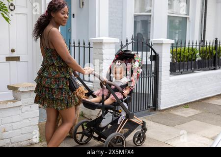 Mutter geht mit Baby-Tochter (12-17 Monate) im Kinderwagen spazieren Stockfoto