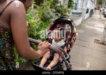 Mutter geht mit Baby-Tochter (12-17 Monate) im Kinderwagen spazieren Stockfoto