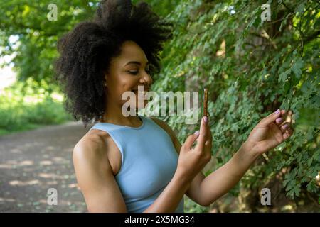 Junge Frau mit Smartphone im Wald Stockfoto