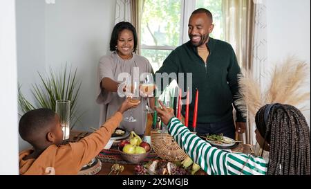 Familie mit Kindern (8-9, 12-13), die während des Kwanzaa-Essens Toast hegen Stockfoto