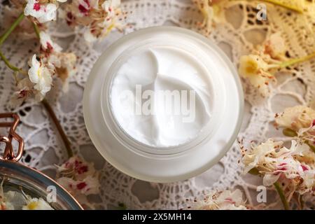 Hausgemachte weiße Rosskastaniencreme in einem Glas auf einem Tisch mit frischer Aesculus hippocastanum-Blüte, die im Frühjahr geerntet wurden Stockfoto