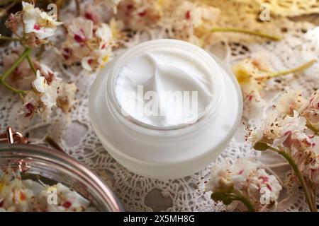 Weiße Rosskastaniencreme in einem Glasgefäß mit frischen Aesculus hippocastanum-Blüten, die im Frühjahr gesammelt wurden Stockfoto