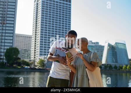 Mann und Frau, die im Sommer in der Stadt ihr Smartphone benutzen Stockfoto