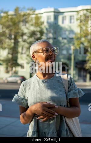 Lächelnde junge Frau, die auf der Stadtstraße steht Stockfoto