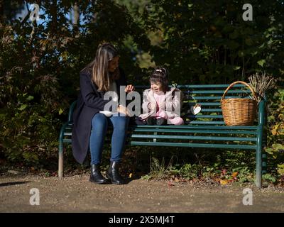 Mutter und Tochter mit Down-Syndrom sitzen auf der Bank Stockfoto