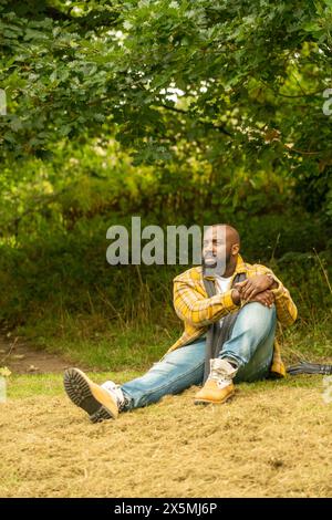 Mann, der sich im Herbst auf dem Rasen im Park entspannt Stockfoto