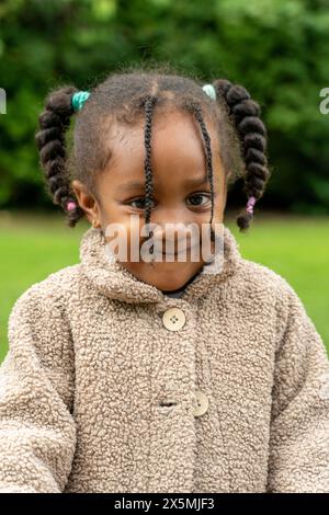 Porträt eines lächelnden Mädchens im Mantel, das im Herbst im Park steht Stockfoto
