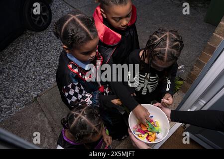 Kinder in Halloween-Kostümen, die nach Süßigkeiten greifen Stockfoto