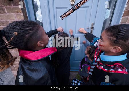 Kinder in Halloween-Kostümen klopfen an die Tür Stockfoto