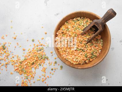 Holzschale mit einer Schaufel trockenem rohen grünen und orangen Erbsenkern auf einem Lichttisch. Stockfoto