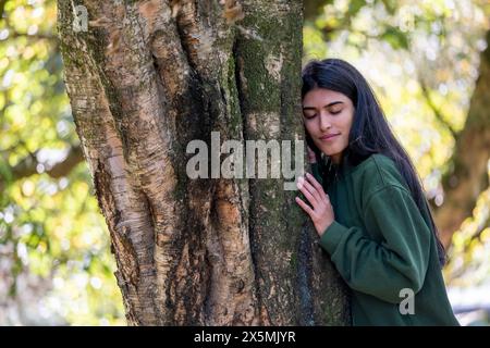 Frau lehnt sich auf einen Baum im Wald Stockfoto