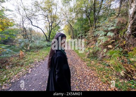 Porträt einer Frau, die im Wald auf einem Fußweg steht Stockfoto