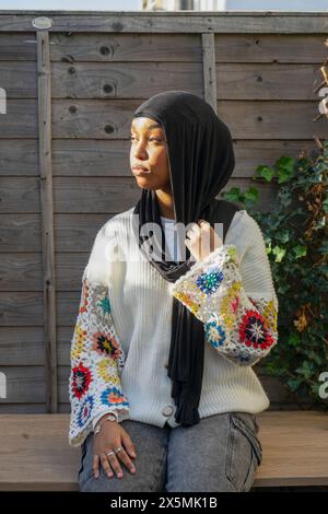 Porträt einer Frau mit Hijab, die draußen sitzt Stockfoto