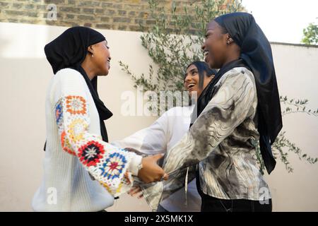 Drei lächelnde Frauen in Hijabs-Begrüßung im Garten Stockfoto