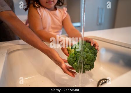 Mädchen, das Brokkoli in der Küchenspüle wäscht Stockfoto