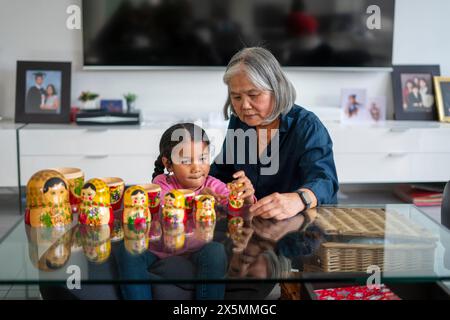 Ältere Frau mit Enkelin, die am Tisch im Wohnzimmer spielt Stockfoto