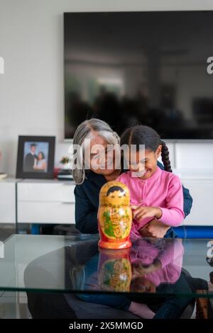 Ältere Frau mit Enkelin, die am Tisch im Wohnzimmer spielt Stockfoto