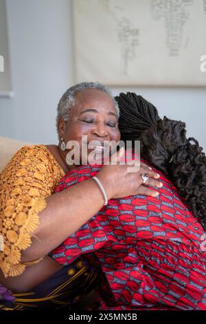 Lächelnde Seniorin umarmt zu Hause die Teenager-Enkelin Stockfoto