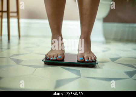 Nahaufnahme der Beine einer Frau, die auf der Badezimmerwaage steht Stockfoto