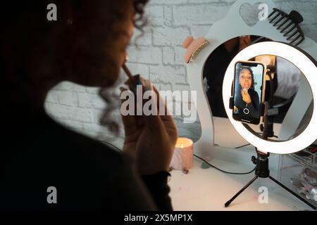 Ein Teenager trägt Lippenglanz auf, während er zu Hause Make-up-Videos filmt Stockfoto