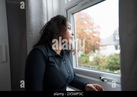 Nachdenkliches Teenager-Mädchen, das durch das Fenster schaut Stockfoto