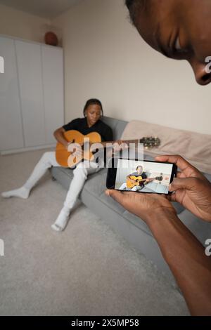 Ein Teenager-Junge, der einen Freund aufnimmt, der zu Hause Gitarre spielt Stockfoto