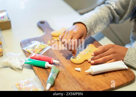 Nahaufnahme eines Mädchens, das Lebkuchenkekse in der Küche dekoriert Stockfoto