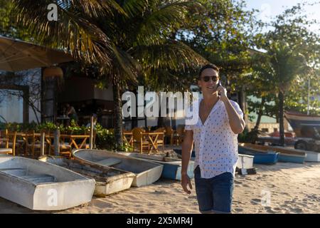 Mann, der am Strand entlang läuft und telefoniert Stockfoto