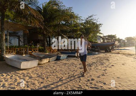 Mann, der am Strand entlang läuft und telefoniert Stockfoto