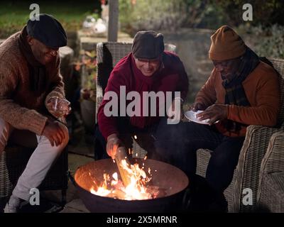 Männliche Freunde, die sich an der Feuerstelle entspannen Stockfoto