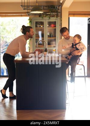 Schwulenpaar, das die Tochter in der Küche ernährt Stockfoto