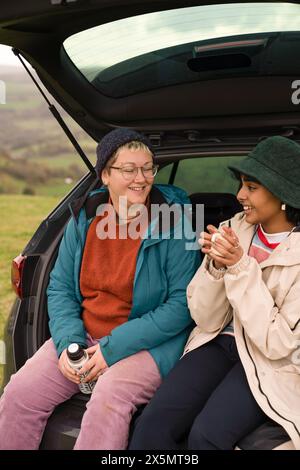 Weibliche Freunde sitzen nach dem Wandern im Kofferraum Stockfoto